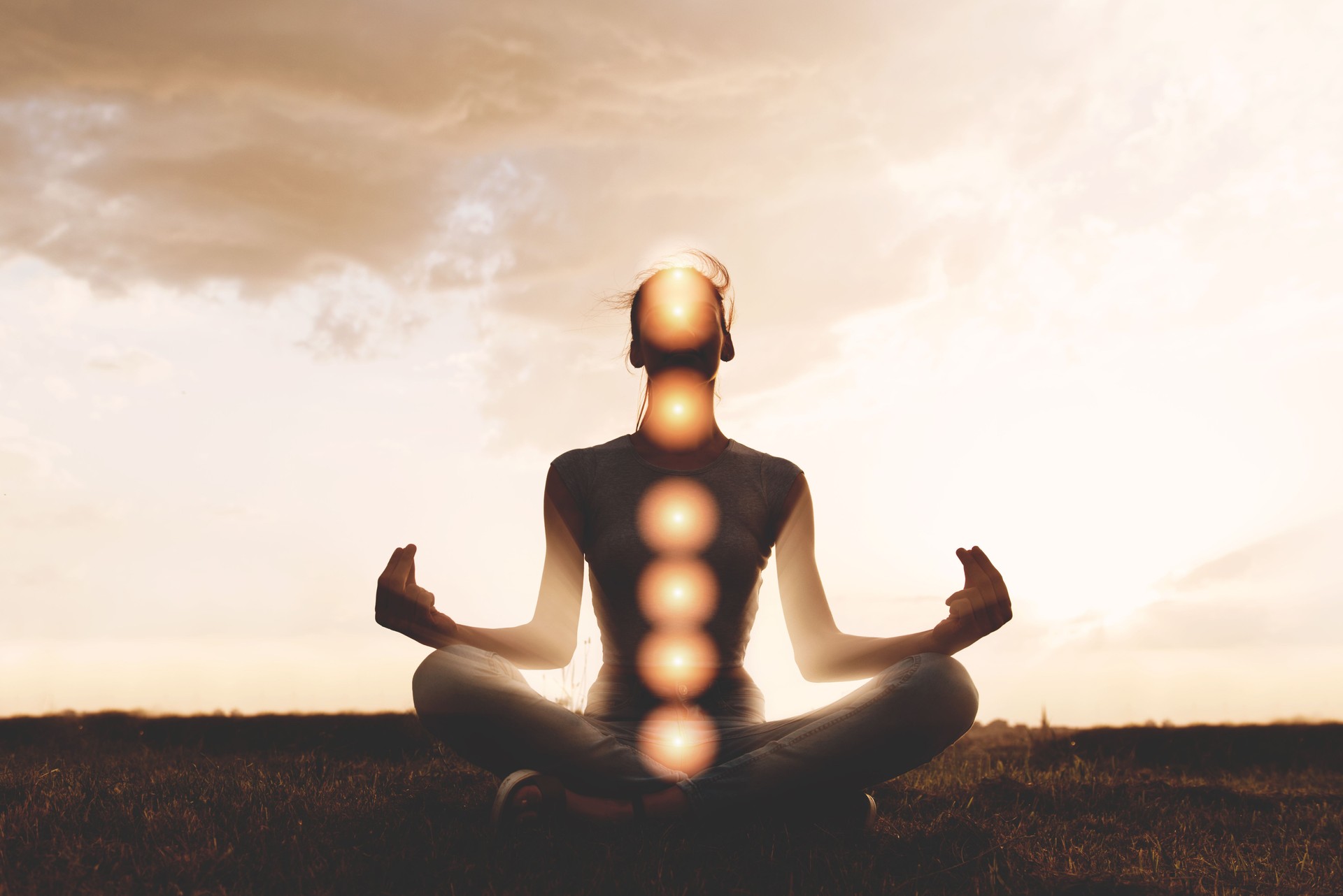 Woman practicing meditation in sunset, with chakras